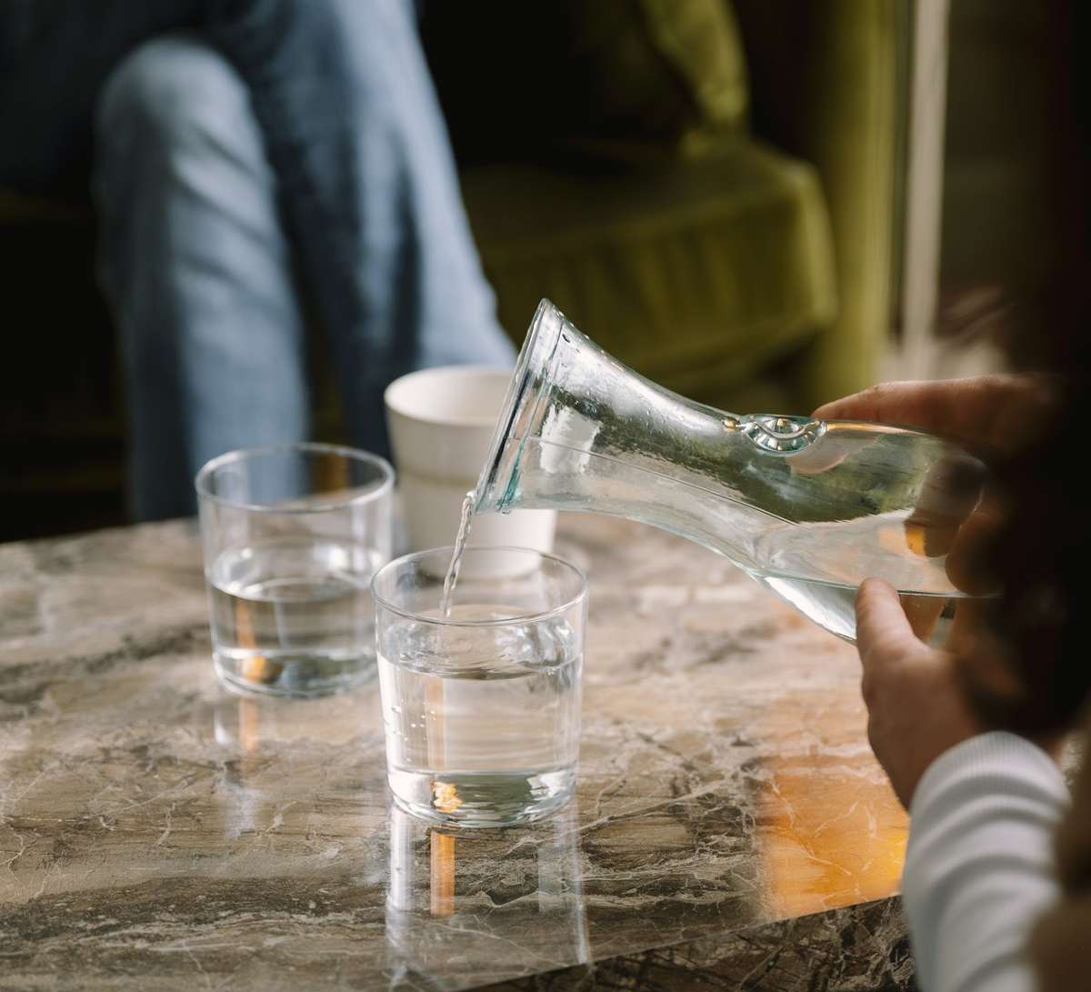Iris schenkt water in aan de salontafel in de praktijk
